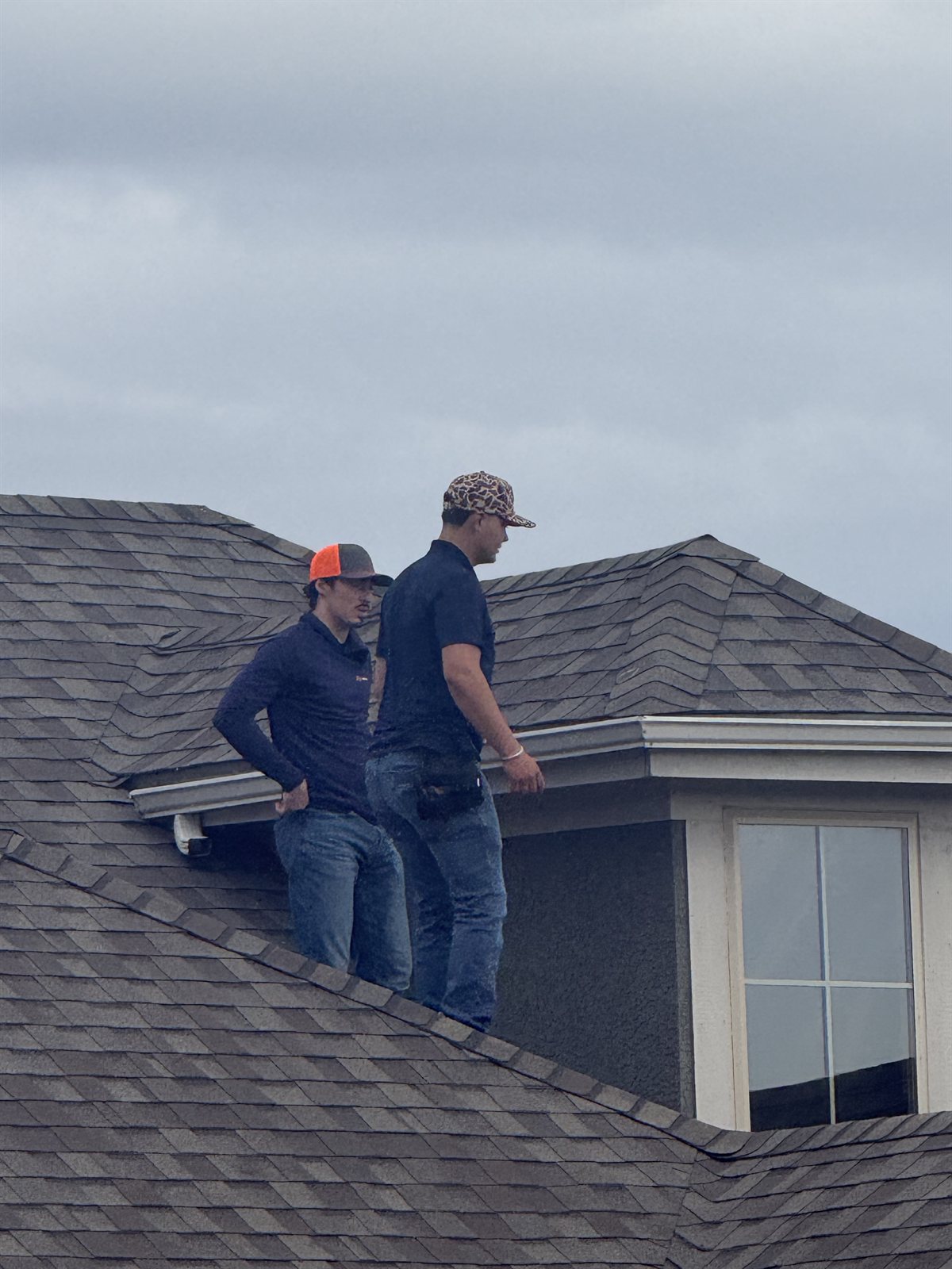 Two MCO team members inspecting a roof beside a dormer